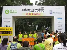 Four trailrunners posing under finish line banner, with crowd of people in foreground