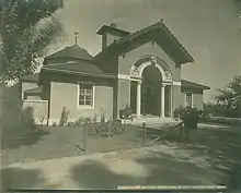 A black and white photo of an archway leading into a building with sculptures of exotic animals.