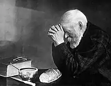 Grace, a black and white photo of a bearded man bowed in prayer