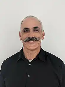 Evan Prodromou smiling and facing the camera with his back against a white background