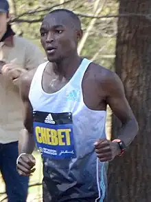 Black man in a white and black top running.