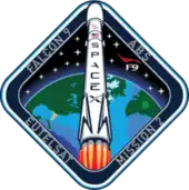 A diamond-shaped emblem with blue borders encasing an artistic depiction of a Falcon 9 rocket launching to space.