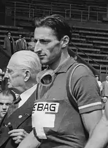 Black-and-white image of a man in a shirt with a cross.