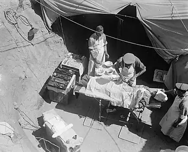 Photo by Ernest Brooks of a surgeon removing a bullet from a soldier's arm in a field-ambulance tent of the East Lancs Territorials at Cape Helles, Gallipoli, in 1915 → August 7, 1915, 2 (51): 584