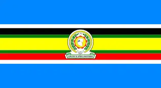 Nine horizontal strips coloured (from top to bottom): blue, white, black, green, yellow, green, red, white, then blue. The logo of the EAC is placed in the centre.