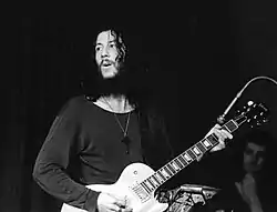 Black and white photo of Peter Green from the waist up playing a Les Paul Gibson with a reversed neck pickup