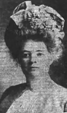 A young white woman wearing her hair in a high bouffant arrangement with flowers and ribbons.