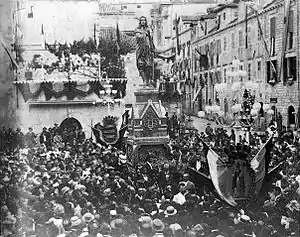 Mass of people around a statue.