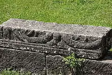 Color photograph of an engraved stone block resting on other blocks.