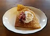 A sweet crêpe filled with oats and berries and topped with whipped cream