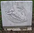 Marble plaque with an outlay of a feather linked to a piece of chain, and the name "Gilbert Stuart" carved on it.