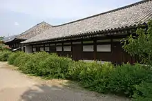 Long wooden building with white walls.