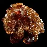 A cluster of orange to red almandine garnet crystals.