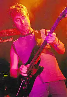 A man playing an electric guitar in reddish stage lighting