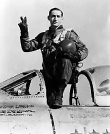 A man standing in the cockpit of an aircraft that is on the ground.