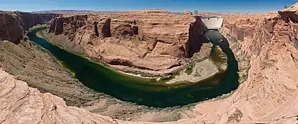 A wide view of the dark green Colorado River below Glen Canyon Dam.