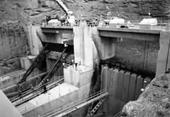 View of two large gates separated by concrete piers, holding back floodwater.