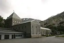 Large dark building with snow-capped mountains at the rear