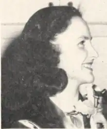 A young white woman, smiling, with long loose dark wavy hair; in profile