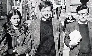 A black and white photograph showing a woman and two men walking down a street in Madrid