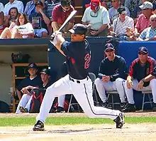 A man in a navy baseball jersey and white pants