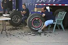 two people use knives to cut grooves in tyres