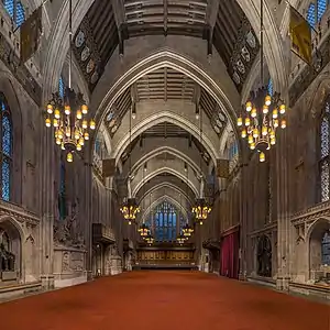 A large medieval hall with pointed arches and a red carpet