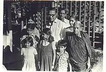 A black and white photo of H. R. Janardhana Iyengar with his wife, daughter and grandchildren in front of his house in the late 1970s