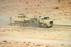 An Oshkosh M1070A1 HET and a DRS M1000 semi-trailer hauling a M2 Bradley IFV