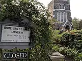 The foreground sign is at the entrance to the Home Sweet Home museum; the building in background is St. Luke's Church