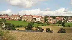 A row of red houses behind a large grassy area.