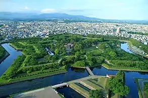 Bird eye view on a star shaped fortress with surrounding water filled moat.