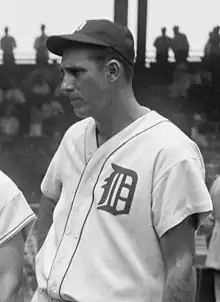 A man in a light baseball jersey and dark cap