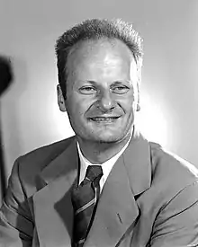 A portrait of a man looking a bit to the side wearing a suit