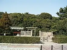 Torii gate and trees behind a stone fence.