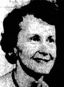 A smiling white woman of about sixty years, with short dark hair in a set style