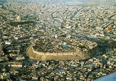 Hill with houses on top and surrounded by urban sprawl