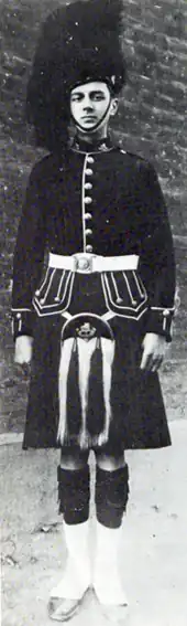 Clean-shaven young white man in Scottish military dress uniform, with kilt and bearskin