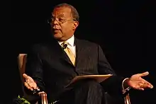 Gates seated, wearing formal attire