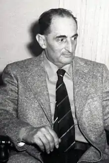 Henry Winterfield seated, in a jacket and tie.