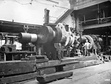 Finishing the ends of a crankshaft after building; an improvised lathe for machining a large steam engine crankshaft, 1900 with a worm and wheel for turning the shaft in the centre. In the background on the far right is a screw cutting machine.