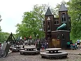 dark brown wooden structure resembling a castle with circular tables in front