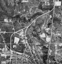 Aerial photograph of several roads intertwined around a valley. The lower half of the image shows some suburban development, while the northern half is mostly undeveloped