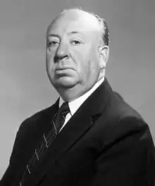 Black and white image shows head and shoulders shot of a man dressed in suit and tie.