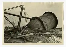 Photograph of a toppled water tower with a mangled support structure