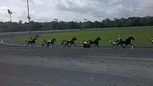 There are six horses racing at Rosecroft Raceway during a qualifying race.