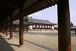 A semi-open wooden corridor with white walls.