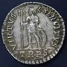 Silver coin showing a man standing with a standard and a round shield behind his legs. There is writing round the edge including "TRPR" below the figure.