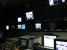 TV director's console, with many monitors on wall