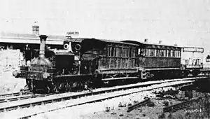 Steam locomotive with three different designs of carriage, at a railway station